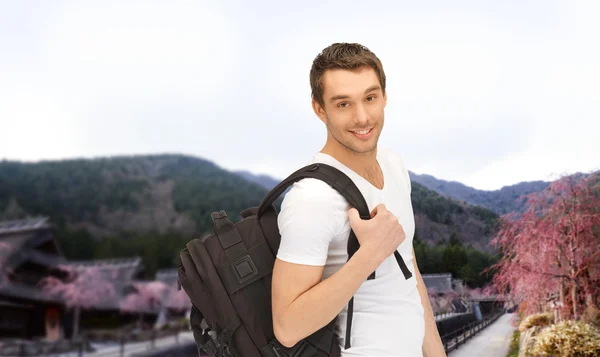 Glücklicher junger Mann mit Rucksack und Buch unterwegs — Stockfoto