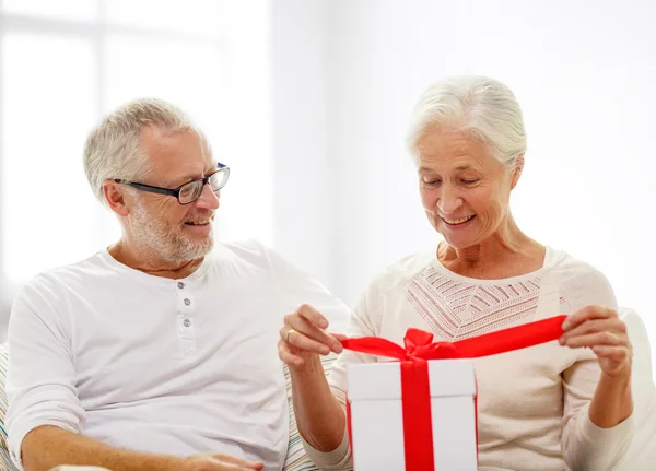 Feliz pareja de ancianos con caja de regalo en casa —  Fotos de Stock