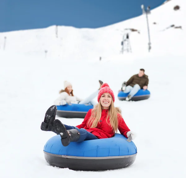 Group of happy friends sliding down on snow tubes — Stock Photo, Image
