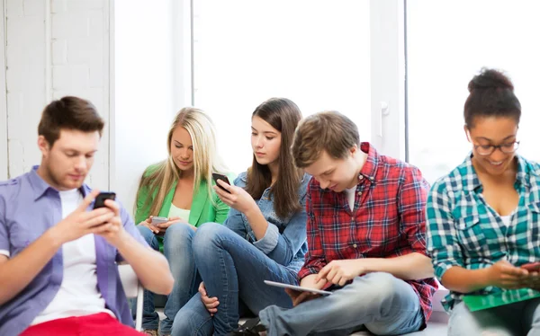 Estudiantes mirando dispositivos en la escuela — Foto de Stock