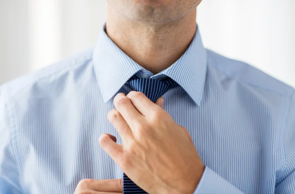 Close up de homem na camisa ajustando gravata no pescoço — Fotografia de Stock