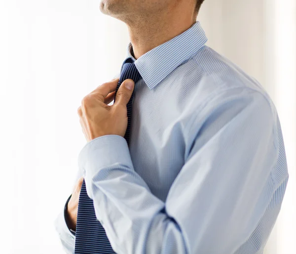 Zamknij się człowieka w koszuli dostosowując krawat na szyi — Zdjęcie stockowe