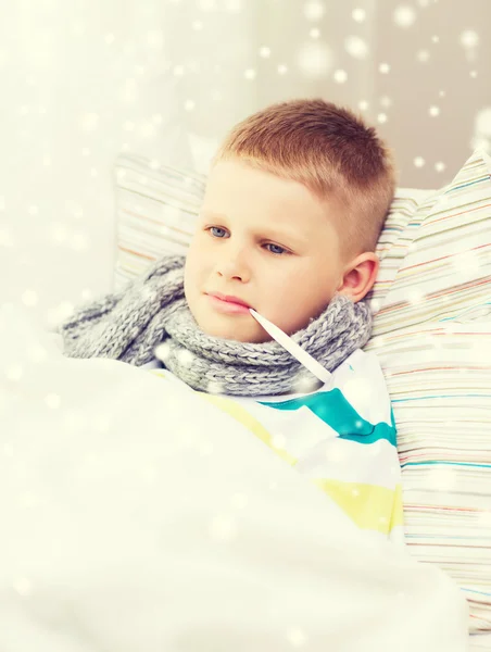 Ill boy with thermometer lying in bed at home — Stock Photo, Image