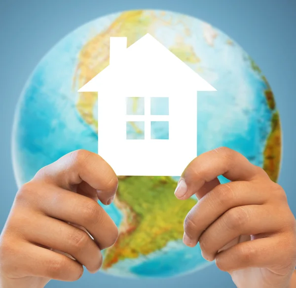 Couple hands holding green house over earth globe — Stock Photo, Image