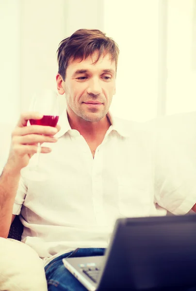 Uomo con computer portatile e bicchiere di vino rosato — Foto Stock