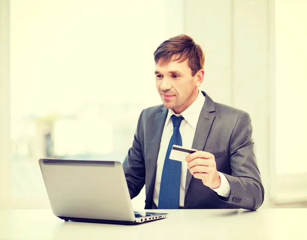 Hombre con portátil y tarjeta de crédito en la oficina — Foto de Stock