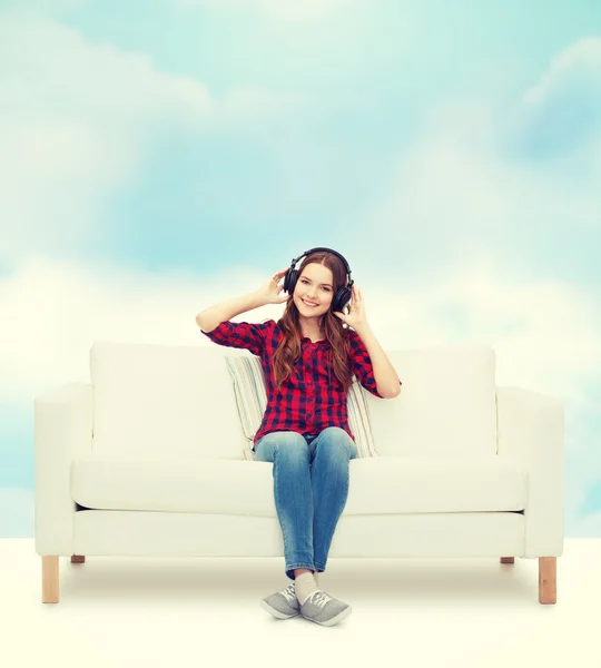 十几岁的女孩坐在沙发上戴着耳机 — 图库照片