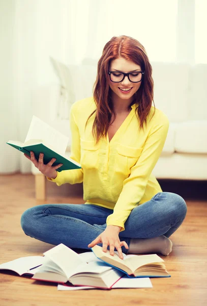 Chica estudiante sonriente leyendo libros en casa — Foto de Stock