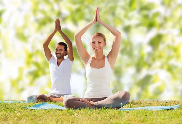 Smiling couple making yoga exdoors — Stok Foto