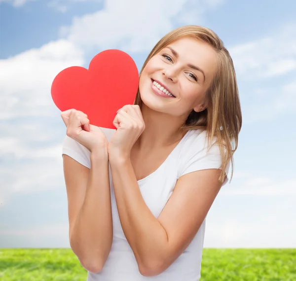 Lachende vrouw in wit t-shirt houden rood hart — Stockfoto