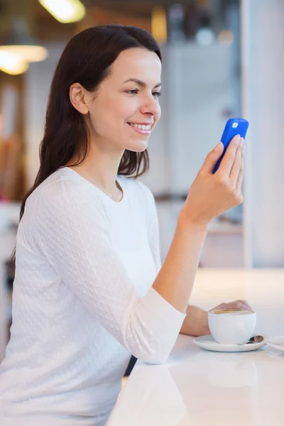 Усміхнена жінка зі смартфоном і кавою в кафе — стокове фото