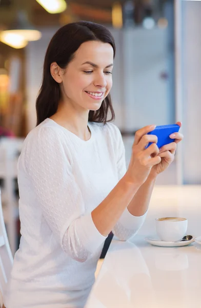 Mulher sorridente com smartphone e café no café — Fotografia de Stock