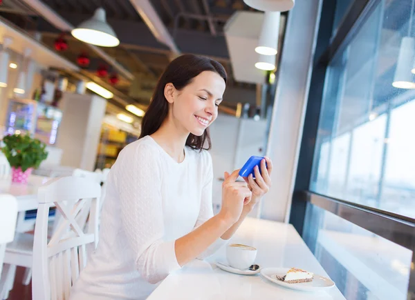 Mulher sorridente com smartphone e café no café — Fotografia de Stock