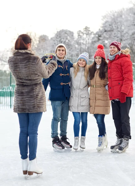 Amis heureux avec smartphone sur patinoire — Photo