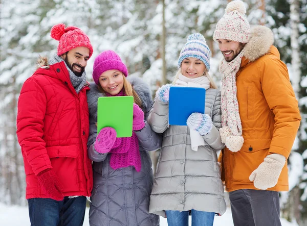 Lachende vrienden met tablet pc in winter forest — Stockfoto