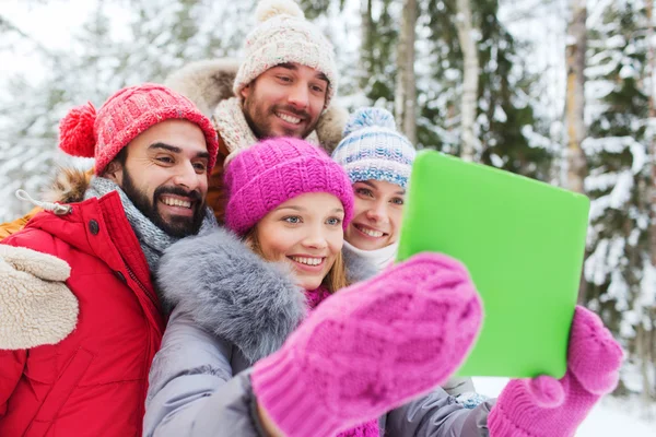 Lachende vrienden met tablet pc in winter forest — Stockfoto