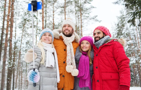 Uśmiechnięty znajomych z smartphone w zimowym lesie — Zdjęcie stockowe