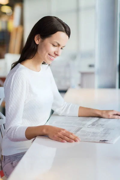 Sonriente joven leyendo el periódico en la cafetería — Foto de Stock