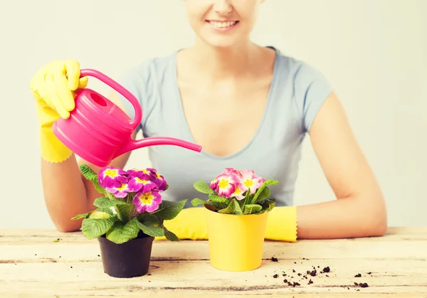 Huisvrouw met bloem in pot en gieter — Stockfoto