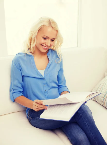 Sorrindo mulher ler livro e sentado no sofá — Fotografia de Stock