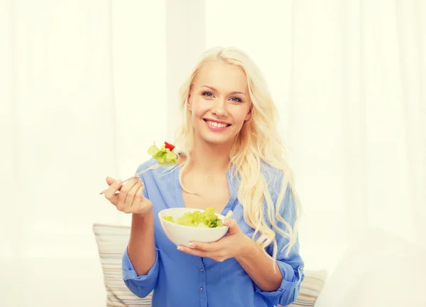 Uśmiechnięta młoda kobieta z zieloną sałatą w domu — Zdjęcie stockowe