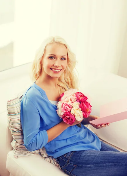 Smiling woman with card and bouquet of flowers — Stock Photo, Image