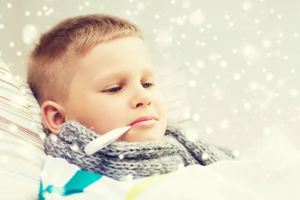 Niño enfermo con termómetro acostado en la cama en casa — Foto de Stock