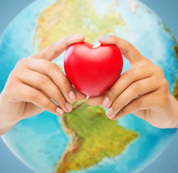Kvinna händer med rött hjärta över jorden världen — Stockfoto
