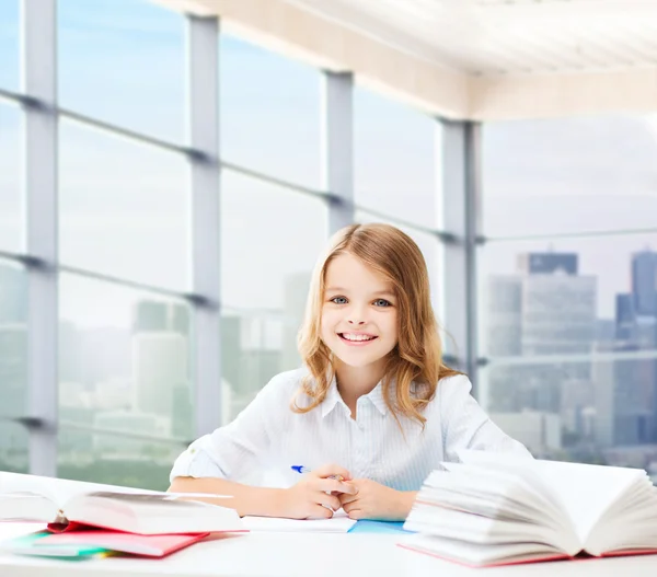 Chica feliz con libros y cuaderno en la escuela — Foto de Stock