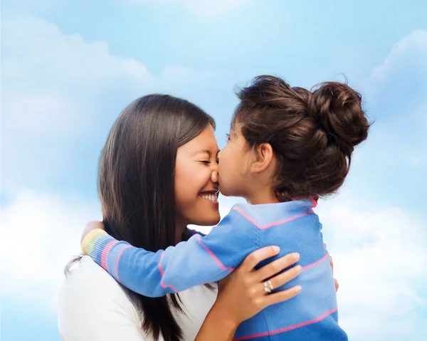 Счастливая маленькая девочка обнимает и целует свою мать — стоковое фото