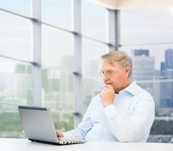 Uomo più anziano in occhiali con computer portatile a ufficio — Foto Stock