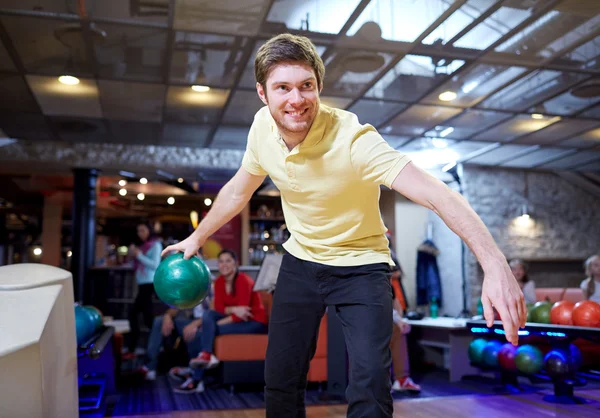 Felice giovane uomo che lancia palla nel bowling club — Foto Stock