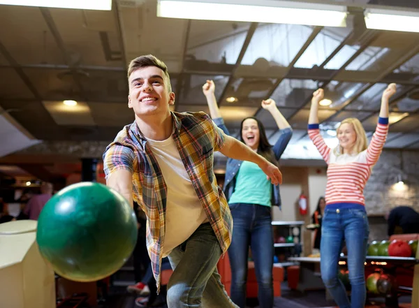 Happy young man throwing ball in bowling club — Stock Photo, Image