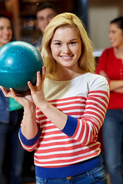 Feliz jovem mulher segurando bola no bowling clube — Fotografia de Stock