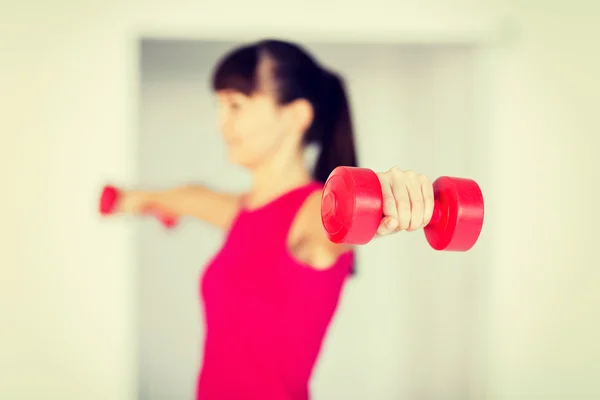 Спортивная женщина руки с легкими красными гантелями — стоковое фото