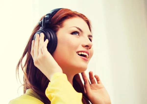 Smiling young girl in headphones at home — Stock Photo, Image