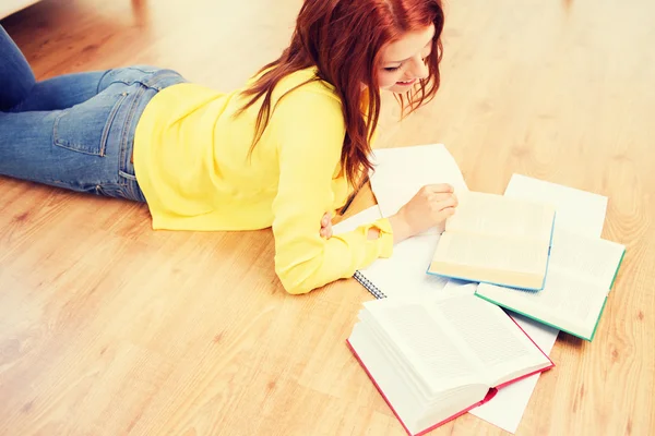 Lächelndes Teenager-Mädchen liest Bücher auf dem Fußboden — Stockfoto