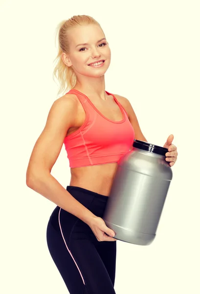 Smiling sporty woman with jar of protein — Stock Photo, Image