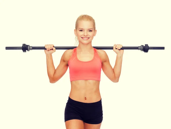 Sorrindo mulher desportiva exercitando com barbell — Fotografia de Stock