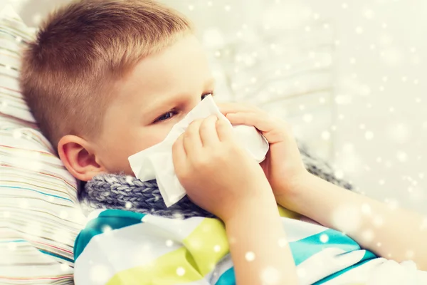 Ziek jongen blazen neus met weefsel thuis — Stockfoto