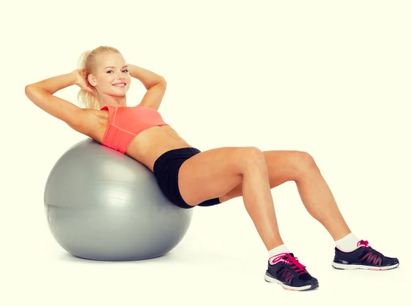 Sorrindo mulher desportiva exercitando na bola de fitness — Fotografia de Stock