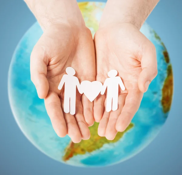 Male hands with paper gay couple figures and globe — Stock Photo, Image