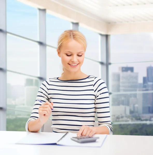 Glückliche Frau mit Notizbuch und Taschenrechner — Stockfoto