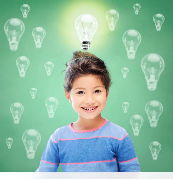 Sonriente niña de la escuela sobre bombillas — Foto de Stock