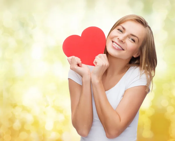 Mujer sonriente en camiseta blanca sosteniendo el corazón rojo — Foto de Stock