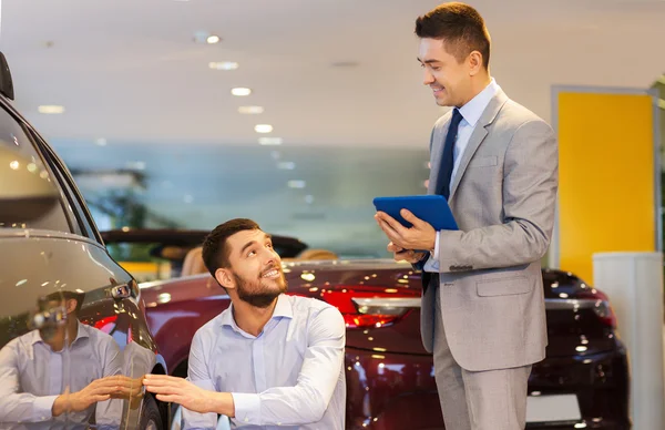 Homem feliz com negociante de carro em auto show ou salão de beleza — Fotografia de Stock