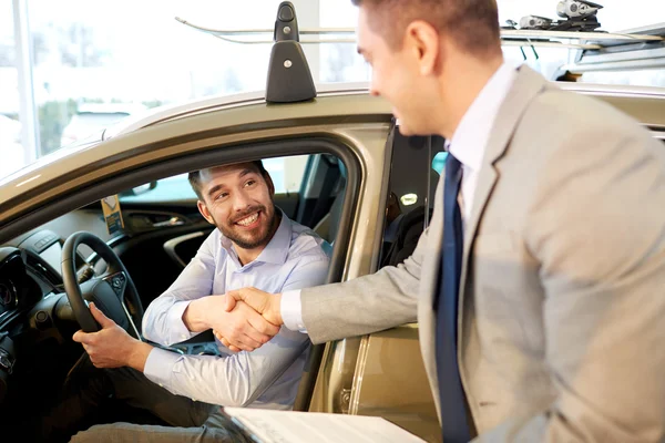 Lycklig man med Bilhandlare i auto visa eller salong — Stockfoto