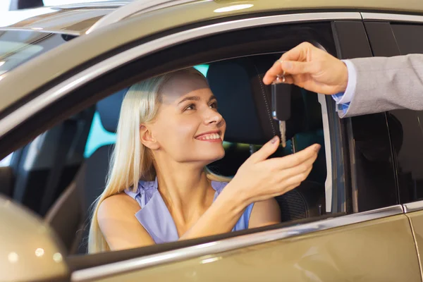 Happy woman getting car key in auto show or salon — Stock Photo, Image