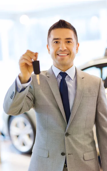 Hombre feliz que muestra la llave en el salón auto del espectáculo o del coche — Foto de Stock