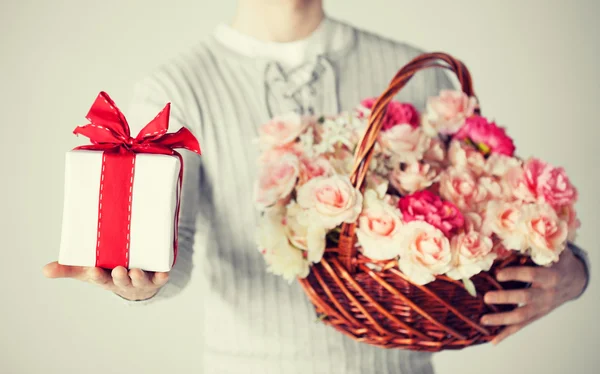 Mann hält Korb voller Blumen und Geschenkbox — Stockfoto